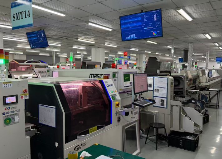 A surface-mount line with a solder-paste printer, conveyors and line monitors, with an SMT14 sign overhead